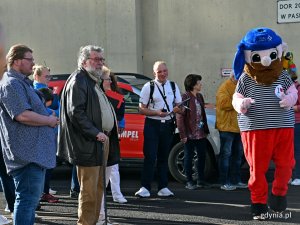  Pasażerowie wycieczkowca „AIDAdiva” i pirat - maskotka Portu Gdynia przysłuchujący się koncertowi Młodzieżowej Orkiestry Dętej „Begama”