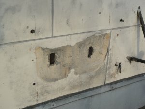 Płyta okładziny kamiennej budynku przy ul. 10 Lutego 24 ze zniszczeniem w miejscu metalowych kotew, które służyły mocowaniu do ściany