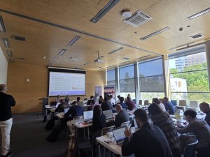 członkowie projektu w sali konferencyjnej uczestniczą w warsztatach, w tle ekran z prezentacją 
