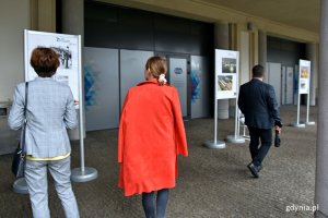 Dwie kobiety i mężczyzna stoją przed tablicami ze zdjęciami. Oglądają wystawę z okazji 70-lecia Kolei Aglomeracyjnej w Trójmieście oraz 20-lecia spółki PKP SKM // fot. Magdalena Czernek