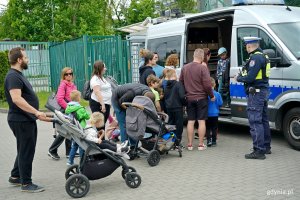 Uczestnicy festynu zaglądający do wnętrza radiowozu policyjnego 