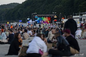 Ludzie siedzą na plaży, w tle scena.