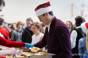 Jeden z wolontariuszy roznoszący świąteczne potrawy gościom wigilii dla samotnych i potrzebujących