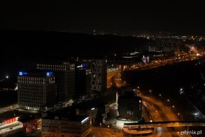 Nocne zdjęcie budynków, w których są zgaszone światła, stojących przy oświetlonych ulicach