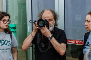 Mężczyzna robiący zdjęcie oraz dwie obserwujące go kobiety