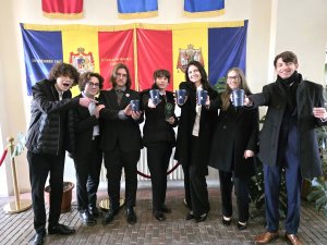 Młodzi ludzie z kubkami w dłoniach, w tle flagii