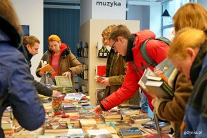 Uczestnicy charytatywnego kiermaszu w Bibliotece Śr&oacute;dmieście podczas przeglądania książek  