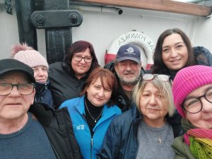 Kobiety i mężczyźni na tle białej ściany z elementami okrętowego wyposażenia