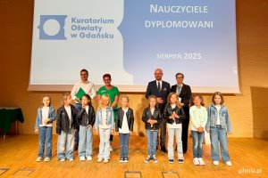 Osoby na scenie pozujące do zdjęcia po wręczeniu nominacji