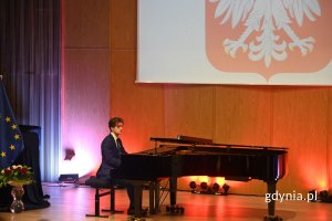 Elegancko ubrany mężczyzna grający na czarnym fortepianie