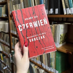 Kobieca dłoń trzymająca książkę „Czerwień”