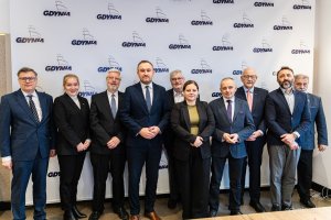 Członkowie Stowarzyszenia Miast Laureatów Nagrody Europy stoją do wspólnego zdjęcia przed ścianką z logo Gdyni