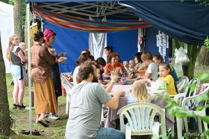 Dzieci i dorośli siedzący przy stole podczas warsztatów w jednej z festiwalowych stref