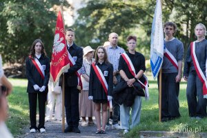 Młodzież w uroczystych strojach ze sztandarem