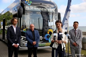 Briefing prasowy na skwerze Arki Gdynia na temat testów autobusu wodorowego. Od lewej: Maciej Stec - wiceprezes zarządu Grupy Polsat Plus, Bogusław Stasiak - prezes Przedsiębiorstwa Komunikacji Miejskiej w Gdyni, Katarzyna Gruszecka-Spychała - wiceprezydent Gdyni ds. gospodarki (przy mikrofonie) oraz Hubert Kołodziejski - dyrektor Zarządu Komunikacji Miejskiej w Gdyni  stoją na tle NesoBusa // fot. Przemysław Kozłowski