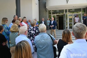 Zebrana publiczność, na schodach szkoły stoi wiceprezydent, w tle budynek szkoły, otwarte drzwi