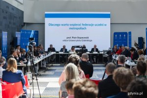 na zdjęciu uczestnicy posiedzenia i debaty, na ekranie tytuł wystąpienia: Dlaczego warto wspierać federacje uczelni w metropoliach