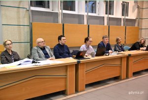 ludzie siedzący przy biurkach w sali obrad