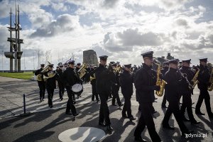 Maszeruje orkiestra w mundurach marynarskich.