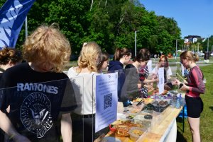 Stoisko III LO, w tle żagle z naoisem Gdynia, las, przy stoisku krząta się grupa uczniów