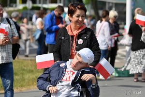 Mieszkańcy z biało-czerwonymi chorągiewkami na skwerze Kościuszki