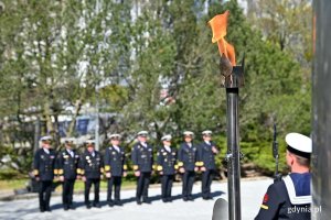 Pochodnia płonąca przed pomnikiem Obrońców Wybrzeża podczas uroczystości z okazji 78. rocznicy zakończenia II wojny światowej. W tle przedstawiciele Marynarki Wojennej RP // fot. Magdalena Czernek