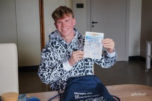 Dominik Kaleta, mieszkaniec Chwarzna-Wiczlina, z kartką z motywem plakatu Jana Rutki na stulecie Gdyni 