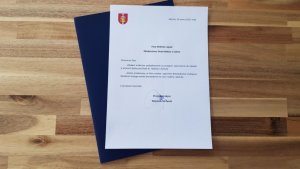 Pismo z podziękowaniem za przyjęcie zaproszenia do udziału w pracach Rady podpisane przez Prezydenta Gdyni Wojciecha Szczurka. Obok granatowa teczka z wytłoczonym logo Gdyni.