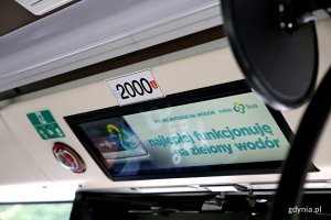 Jeden z cyfrowych wyświetlaczy wewnątrz autobusu. Na biały tle umieszczono morski napis: Najlepiej funkcjonuję na zielony wodór // fot. Przemysław Kozłowski