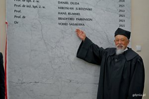 dr Yohei Sasakawa, doktor honoris causa Uniwersytetu Morskiego, wskazujący swoje nazwisko na tablicy pamiątkowej