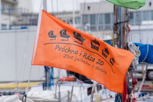 Powiewająca pomarańczowa flaga z napisem: „Próchno i Rdza”. Zlot jachtów z duszą 
