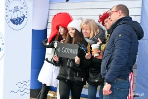 Gdynianie chętnie korzystali z fotobudek. Dwie mieszkanki trzymają tabliczkę z napisem: "Gdynia". Obok nich animatorzy w barwnych kostiumach // fot. Magdalena Czernek