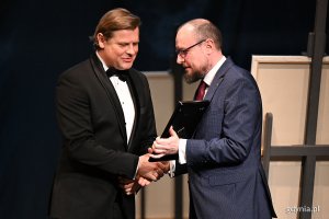 Mariusz Bzdęga - dyrektor zarządzający ds. kultury i aktywności mieszkańców wręcza Nagrodę Prezydent Miasta Gdyni z okazji Międzynarodowego Dnia Teatru  aktorowi Teatru Miejskiego Szymonowi Sędrowskiemu 