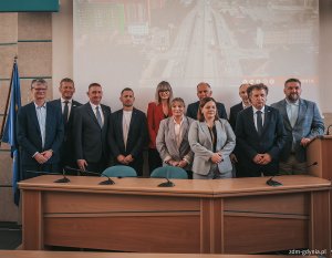 Wsp&oacute;lne zdjęcie podczas konferencji prasowej 26 maja. Od lewej: wiceprezydent Gdyni Rafał Geremek, dyrektor Zarządu Dr&oacute;g Miejskich w Gdyni Michał Felon, dyrektor oddziału GDDKiA w Gdańsku Karol Markowski, pracownicy Zarządu Dr&oacute;g Miejskich, prezydent Gdyni Aleksandra Kosiorek, sekretarz stanu w Ministerstwie Funduszy i Polityki Regionalnej Jacek Karnowski oraz Przewodniczący Rady Miasta Gdyni Tadeusz Szemiot. Wszyscy stoją za stołem prezydialnym w sali obrad (fot. Marcin Mielewski/ Zarząd Dr&oacute;g Miejskich)