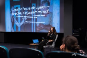 Kobieta z mikrofonem na spotkaniu z uczestnikami wydarzenia