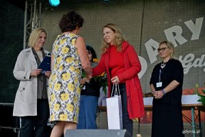 Beata Zastawna &ndash; przewodnicząca Rady Miasta Gdyni i Hanna Niedźwiecka-Pasternak &ndash; zastępca naczelnika Wydziału Ogrodnika Miasta wręczają nagrodę jednej z uczestniczek konkursu &bdquo;Gdynia w kwiatach&rdquo; 
