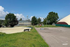boiska szkolne na przestrzeni zielonej, w dalszym tle budynek szkoły i drzewa