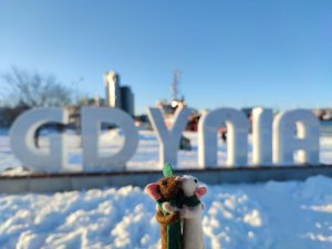 Dwie myszki przytulają się na tle napisu "GDYNIA", znajdującego się na Molo Południowym. Zdjęcie robione zimą, w tle widać śnieg. // fot. Aneta Rychert, Mysie opowieści