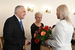 Agata Lipińska, zastępczyni kierownika USC wręcza seniorom kwiaty