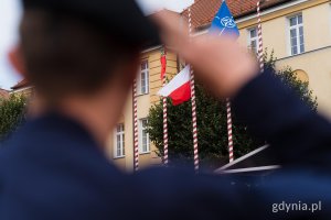 Żołnierz salutujący podczas wciągania flagi państwowej na maszt podczas uroczystej przysięgi wojskowej podchorążych Akademii Marynarki Wojennej 