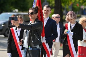Młodzież z biało-czerwonymi szarfami na skwerze Kościuszki