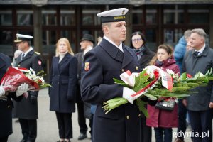 Żołnierze w mundurach Marynarki Wojennej z wiązankami kwiatów