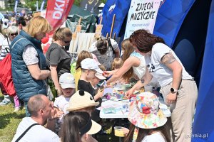 Mieszkańcy na pikniku rodzinnym przy stanowisku z napisem zajęcia muzyczne