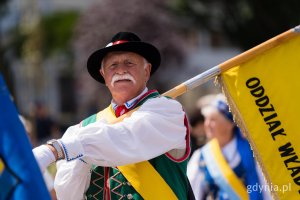 Mężczyzna z wąsem w stroju kaszubskim i flagą: oddział Władysławowo