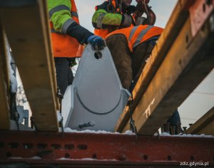 Trwający montaż konstrukcji stalowej wiaduktu drogowego, żelazne elemementy i pracownicy na budowie