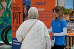 Konsultantka rozmawiająca z mieszkanką przy stoisku informacyjnym loterii &bdquo;Rozlicz PIT w Gdyni&rdquo; w Centrum Handlowym Batory 