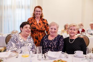 Cztery seniorki pozują do zdjęcia przy zastawionym świątecznie stole