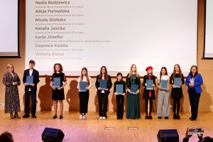 Grupa uczniów stojących na scenie z prezydent Aleksandrą Kosiorek i wiceprezydentką Oktawią Gorzeńską