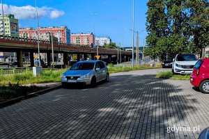 Samochody stojące na parkingu, w tle widoczna estakada