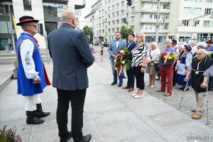 Osoby w ludowych strojach pod pomnikiem